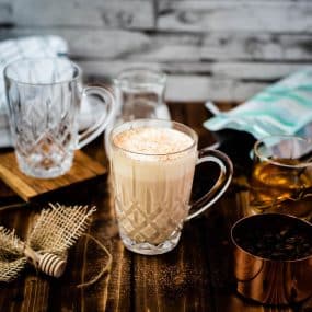 A gorgeous glass of delicious honey latte on dark wooden ground.