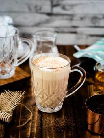 A gorgeous glass of delicious honey latte on dark wooden ground.