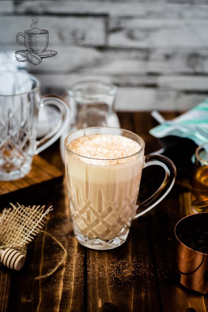 A gorgeous glass of delicious honey latte on dark wooden ground.