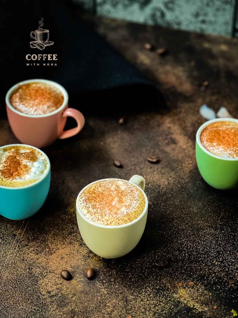 Four cups of coffee on dark brown surface. Milk foam dusted with cocoa.