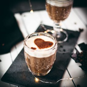 Gorgeous glass filled with coffee con leche on dark slate plate.