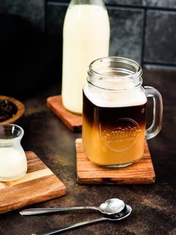 Coffee with coffee creamer in mason glass. Surrounded by containers filled with coffee creamer.