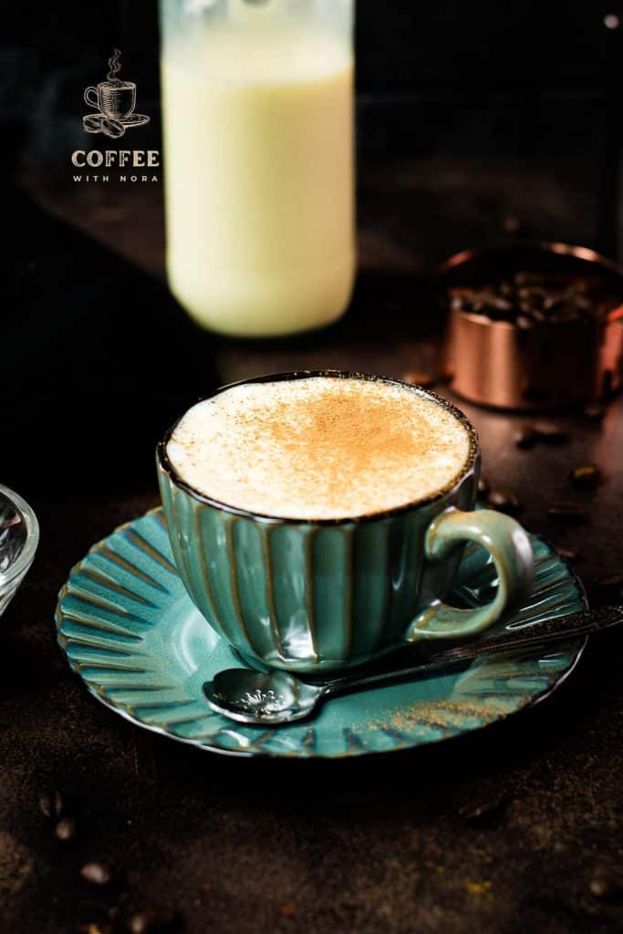 Gorgeous cup of coffee, with homemade coffee creamer. Dusted with cinnamon in a teal cup on a dark background.