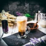 Gorgeous glass filled with iced lavender latte on dark slate plate.