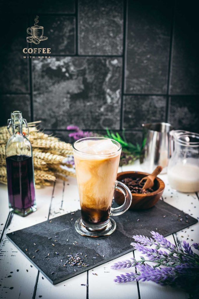 Gorgeous glass filled with iced lavender latte on dark slate plate.