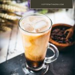 Gorgeous glass filled with iced lavender latte on dark slate plate.