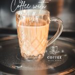 Glass mug filled with coffee and milk placed in microwave.