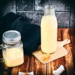 A bottle and a mason jar, filled with scrumptious homemade salted caramel coffee creamer. Placed on wooden board.