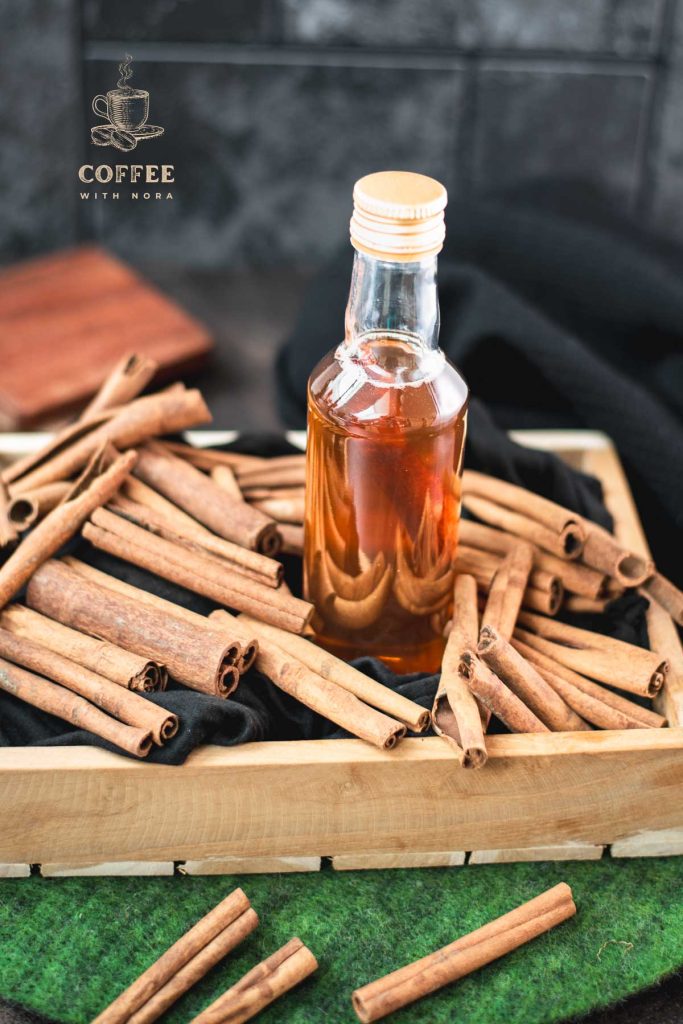 Preserving bottle filled with delectable brown sugar cinnamon syrup placed in wooden basket filled with cinnamon sticks.