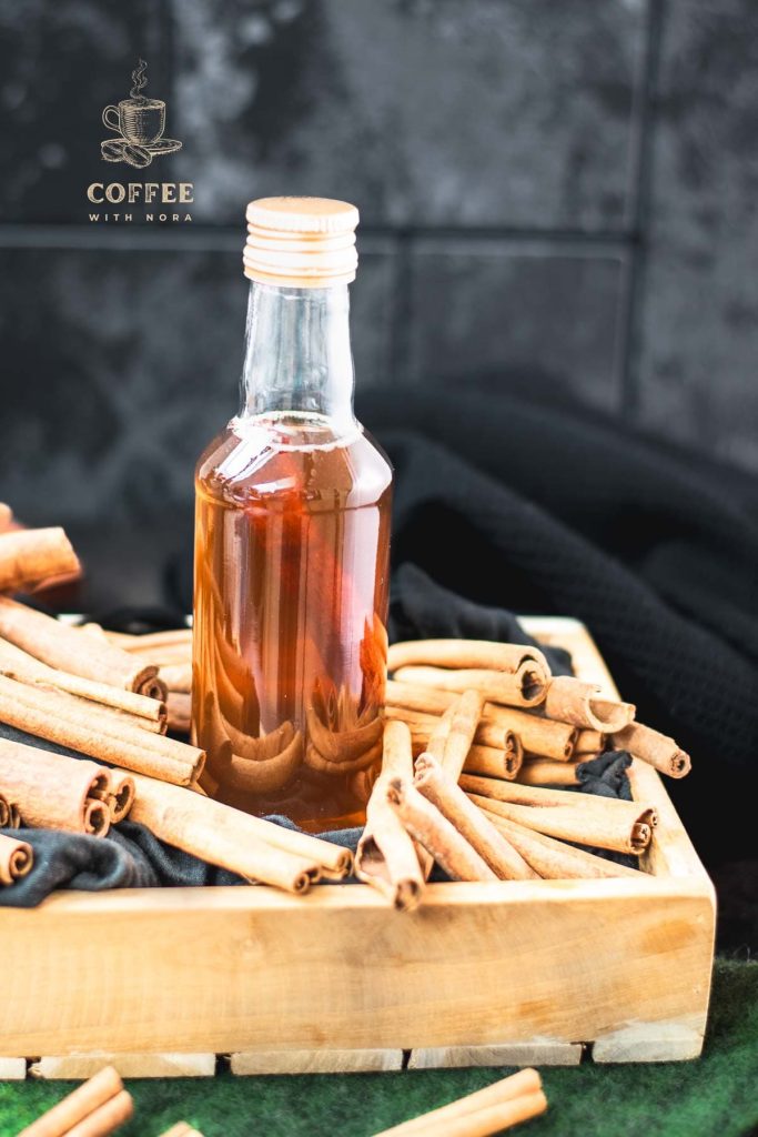 Preserving bottle filled with delectable brown sugar cinnamon syrup placed in wooden basket filled with cinnamon sticks.