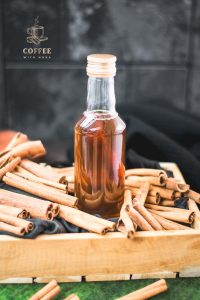 Preserving bottle filled with delectable brown sugar cinnamon syrup placed in wooden basket filled with cinnamon sticks.