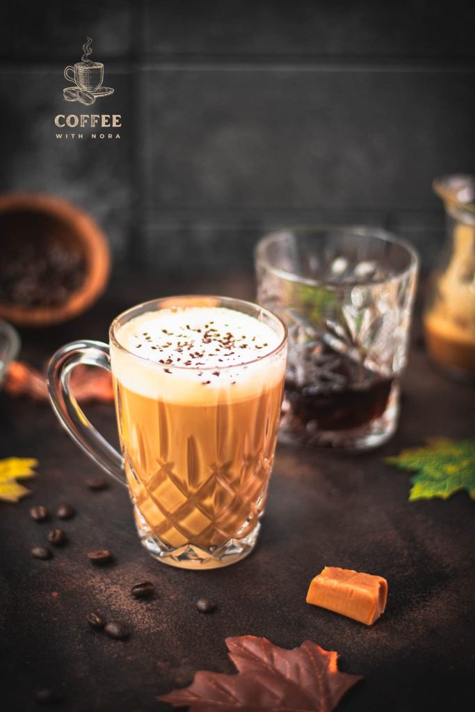 Gorgeous, amber colored caramel coffee with homemade caramel milk filled in glass mug and placed on dark ground.