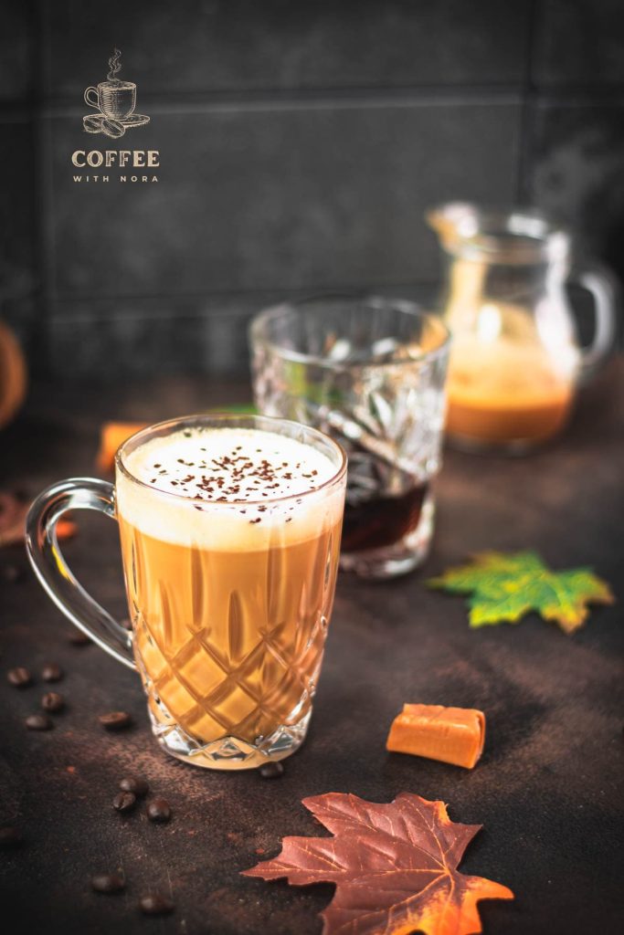 Gorgeous, amber colored caramel coffee with homemade caramel milk filled in glass mug and placed on dark ground.