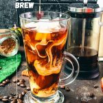 Delicious Pumpkin cream cold brew in gorgeous glass next to French press coffee maker.