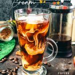 Delicious Pumpkin cream cold brew in gorgeous glass next to French press coffee maker.