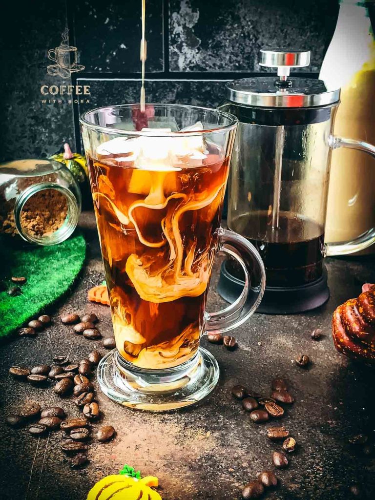 Delicious Pumpkin cream cold brew in gorgeous glass next to French press coffee maker.