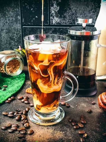 Delicious Pumpkin cream cold brew in gorgeous glass next to French press coffee maker.