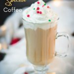 Festive Christmas coffee with homemade Christmas creamer. Topped with whipped cream and sprinkled with Christmassy placed on white ground.