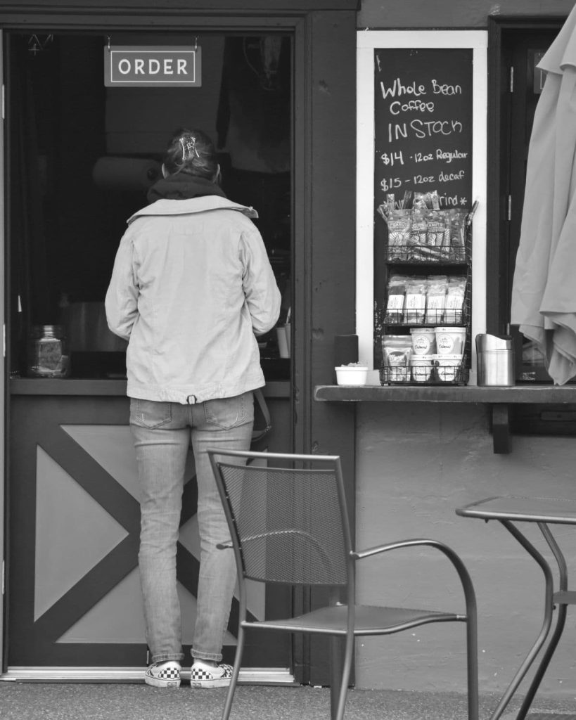 Woman standing at the counter and ordering a coffee.