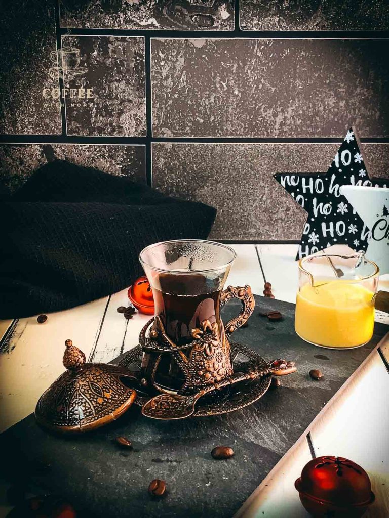 Gorgeous mediaeval coffee glass filled with black coffee placed on black slate plate.