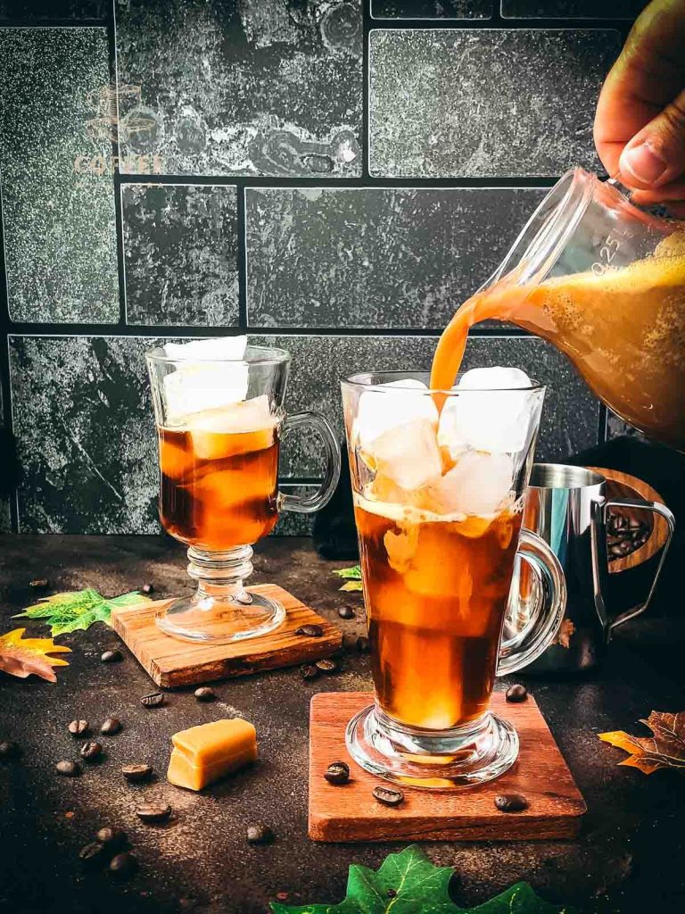 Tall, narrow coffee-filled glass, gets filled with ice-cold homemade caramel milk.