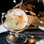 Gorgeous glass filled with iced cinnamon dolce latte. Placed on black slate plate.