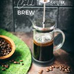 French press filled with cold water and ground coffee next to a bowl of coffee beans - an easy way to make cold brew coffee!