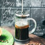 French press filled with cold water and ground coffee next to a bowl of coffee beans - an easy way to make cold brew coffee!