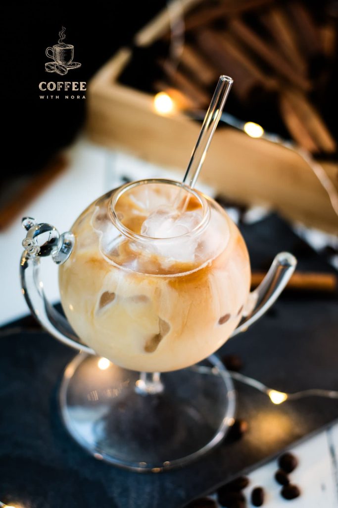 Gorgeous glass filled with iced cinnamon dolce latte. Placed on black slate plate.