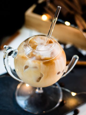 Gorgeous glass filled with iced cinnamon dolce latte. Placed on black slate plate.