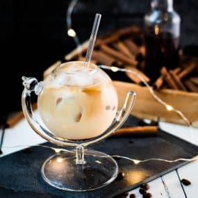 Gorgeous glass filled with iced cinnamon dolce latte. Placed on black slate plate.