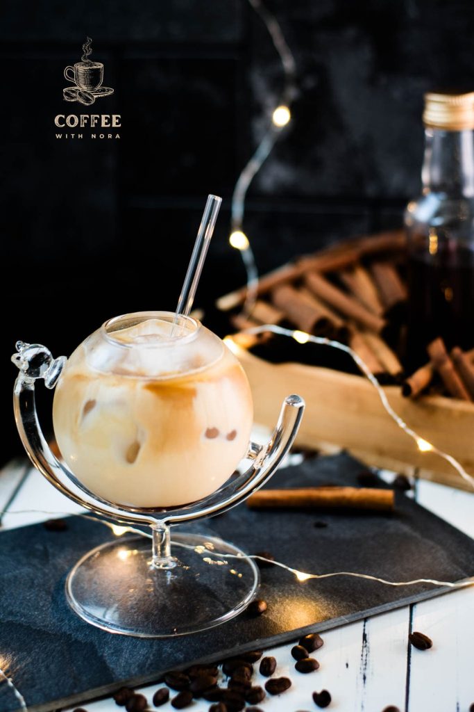 Gorgeous glass filled with iced cinnamon dolce latte. Placed on black slate plate.