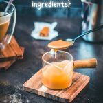 Spoon with homemade caramel sauce hovering over glass jar filled with caramel sauce.