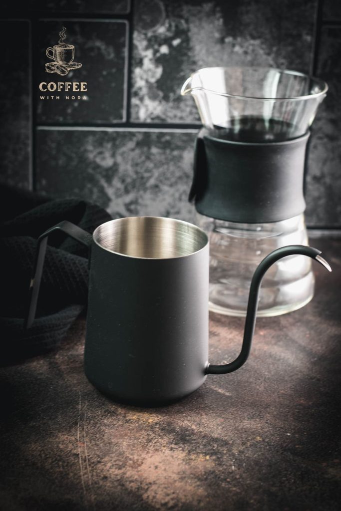 Gorgeous black gooseneck kettle on dark ground placed next to a V60 Pour Over Kit.