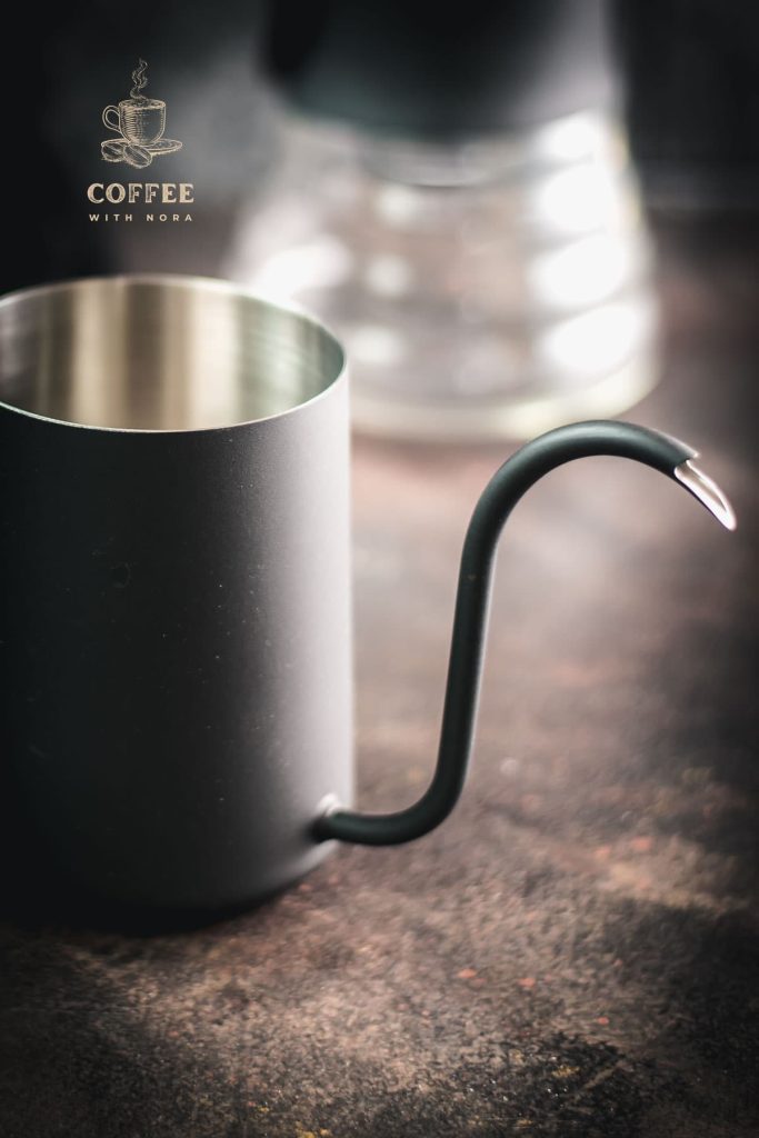 Gorgeous black gooseneck kettle on dark ground placed next to a V60 Pour Over Kit.