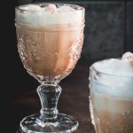 Gorgeous almond milk lattes, in gorgeous glasses, placed on dark floor.