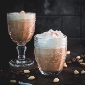 Gorgeous almond milk lattes, in gorgeous glasses, placed on dark floor.