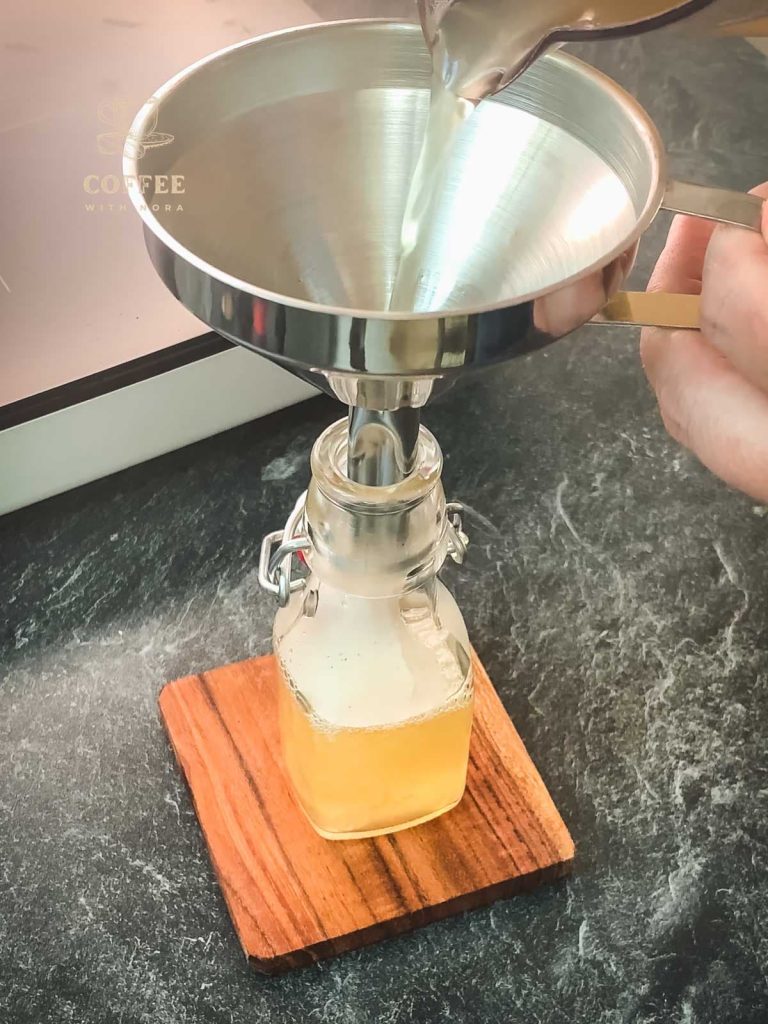 Pour the ginger syrup into the preserving bottle using a funnel.