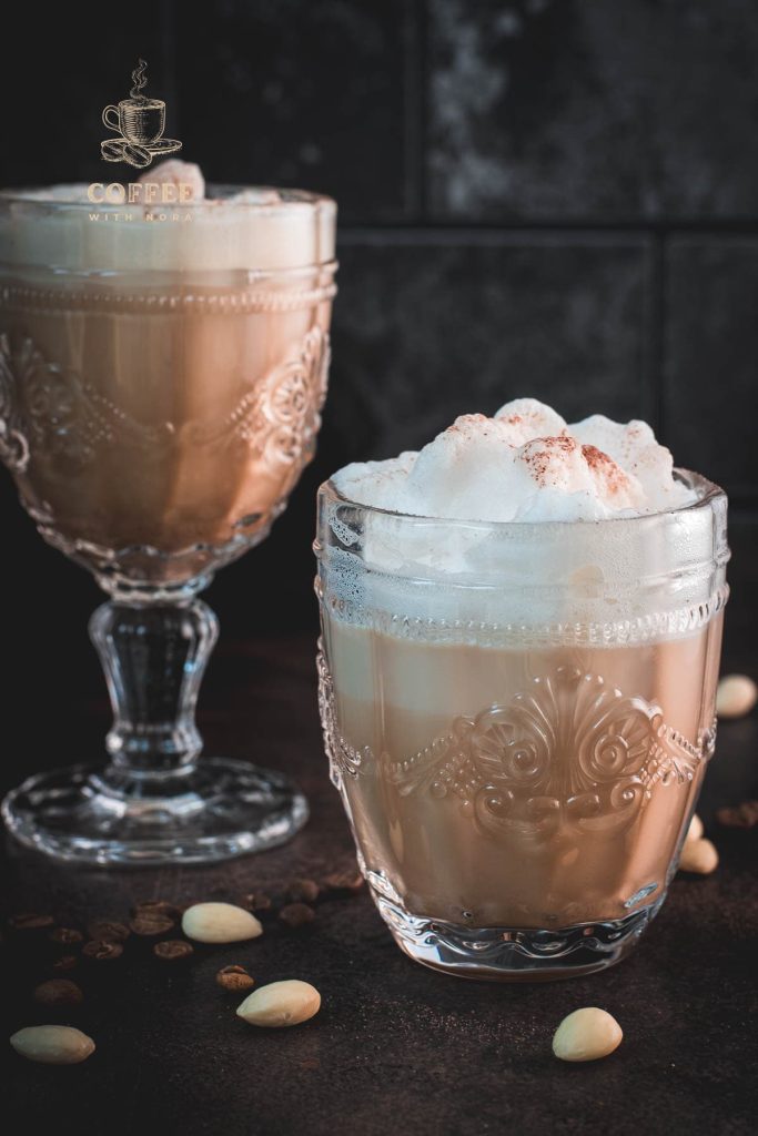 Gorgeous almond milk lattes, in gorgeous glasses, placed on dark floor.