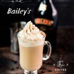 Gorgeous glass filled with scrumptious Bailey's coffee, topped with whipped cream and dusted with cocoa. Placed on dark ground in front of an Salted Baileys Caramel bottle.