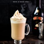 Gorgeous glass filled with scrumptious Bailey's coffee, topped with whipped cream and dusted with cocoa. Placed on dark ground in front of an Salted Baileys Caramel bottle.