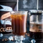 Cute glass filled with French press iced coffee placed next to French press.