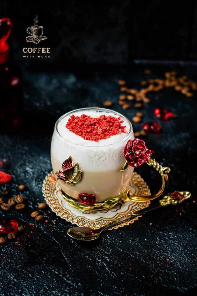 Beautiful coffee glass decorated with a red and gold butterfly and flowers. Filled with delicious strawberry latte and topped with heart-shaped freeze-dried strawberry powder. Placed on dark ground.