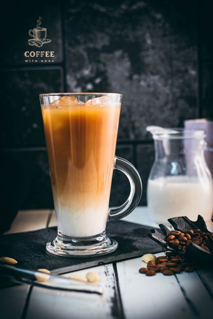 Gorgeous glass filled with ice cold plant based vanilla iced coffee. Placed on black slate plate.