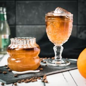 Glass filled with gorgeous, layered, ginger cold brew placed on black slate plate.