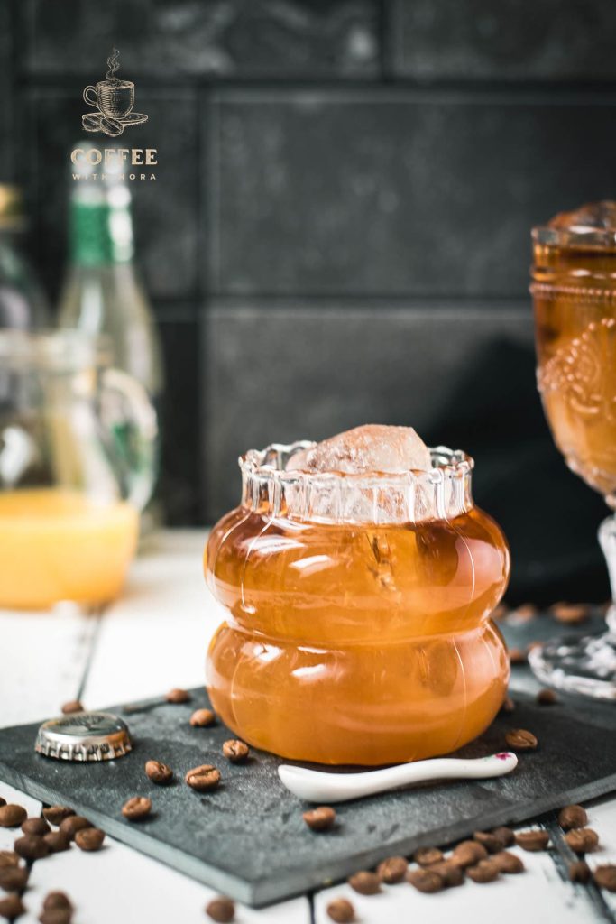 Glass filled with gorgeous, layered, ginger cold brew placed on black slate plate.