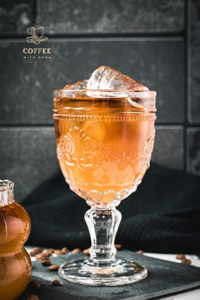 Glass filled with gorgeous, layered, ginger cold brew placed on black slate plate.