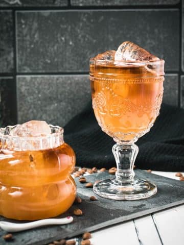 Glass filled with gorgeous, layered, ginger cold brew placed on black slate plate.