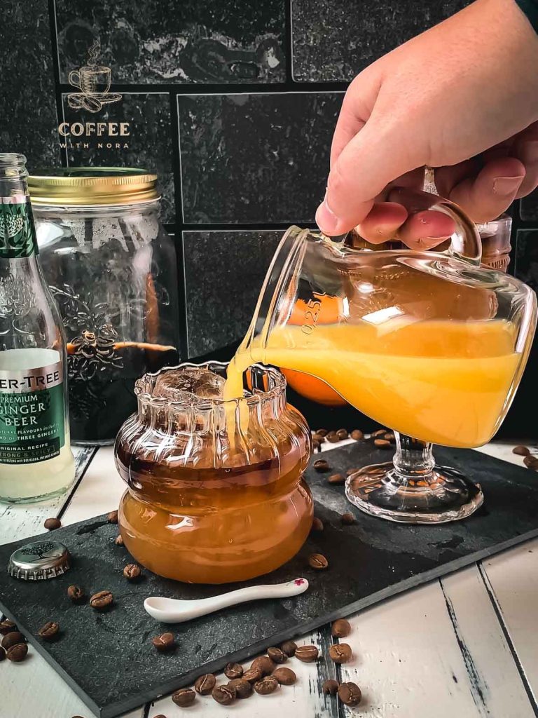 Pour orange juice into the glass layered with ginger beer and cold brew.