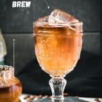 Glass filled with gorgeous, layered, ginger cold brew placed on black slate plate.